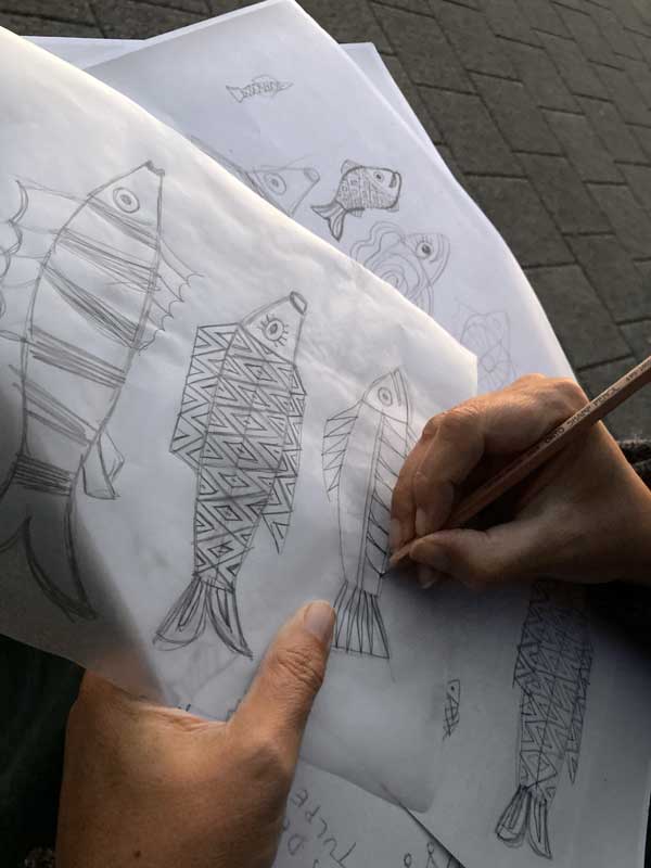 Therese zeichnet Fisch verliebt Fische Motive mit Bleistift auf Trasparentpapier. Es ist schon dämmerig.