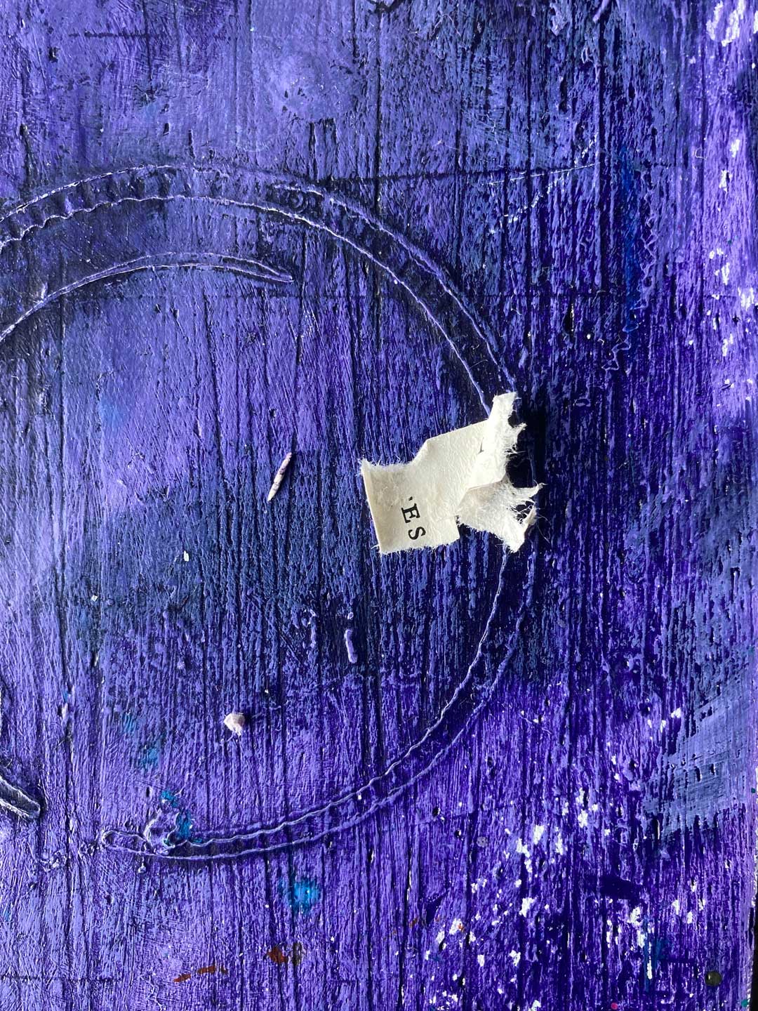 Kleiner Fetzen oder Reststück. Es steht »ES« drauf und liegt auf der bunt lila Arbeitsplatte mit vielen Strukturen.