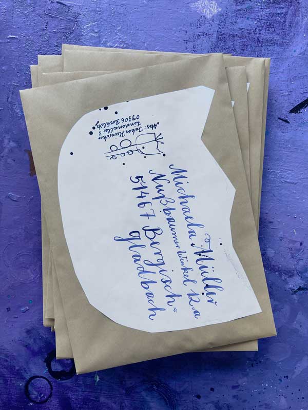 Fertige Umschläge auf einem Stapel. Oben liebgt der Adressierte Brief an Michaela. Eine große Tulpenblüte sehr rudimenär ausgeschnitten diesnt als Adressfeld.