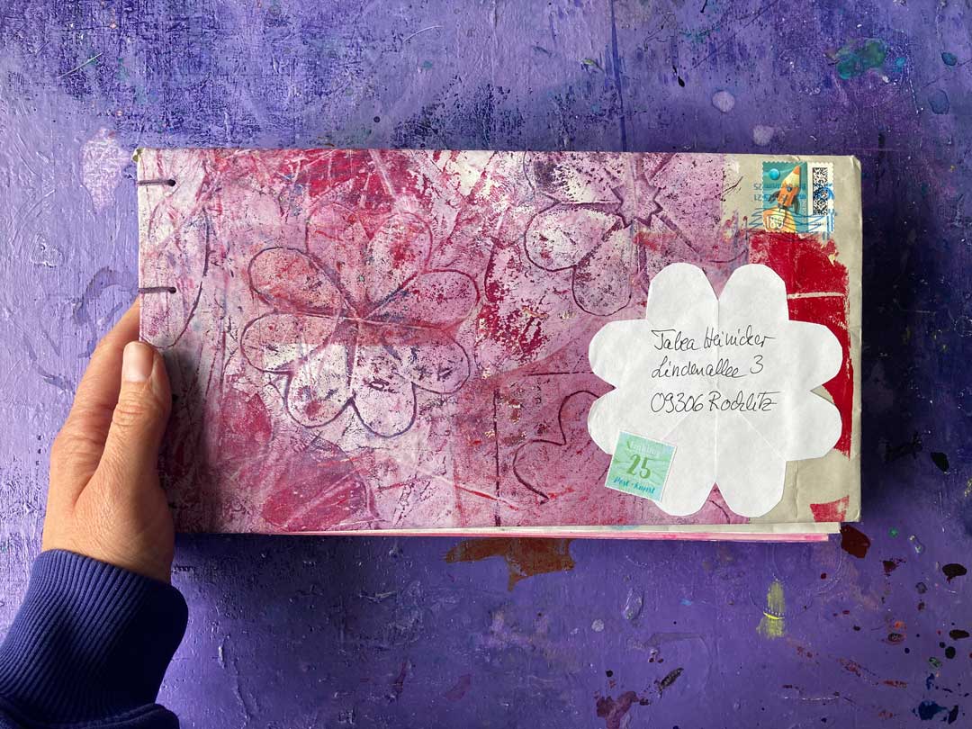 Frontal Ansicht des Buches mit Tabeas Hand. Schönes Musterpapier in Rosa als Umschlag, Handschrift und Adresse, Briefmarke sind zu usehen.