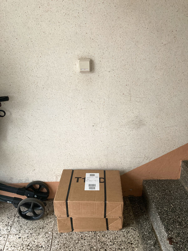 Zwei braune Pakete liegen in einem tristen Hausflur.