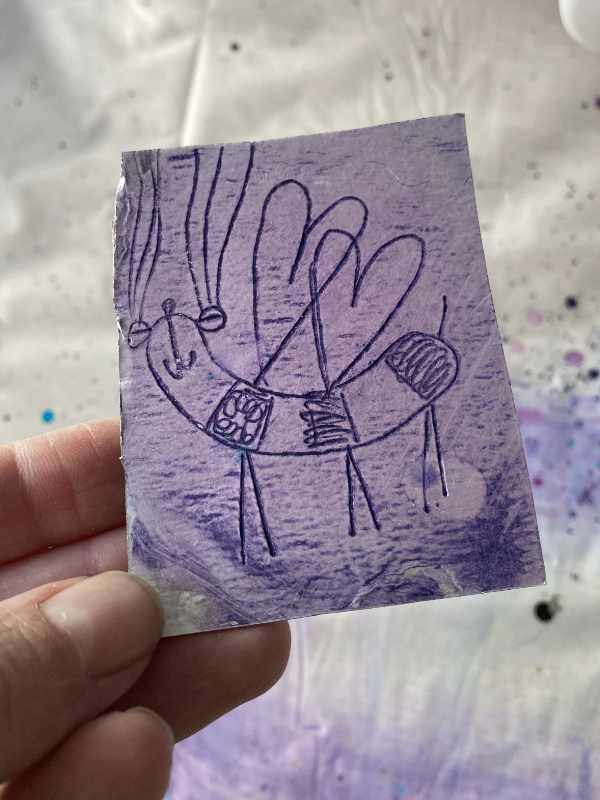 Druckplatte aus Milchtüte. Ein Insekt eingeitzt, die Platte schimmert Rosa. Tabeas Hand hält das Stücl.