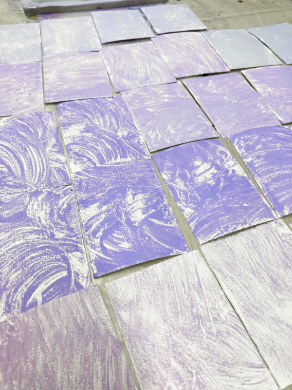 Viele ATC liegen grundiert auf dem Tisch. Wischtechnik-Druck von der Gelliplate. Lila.