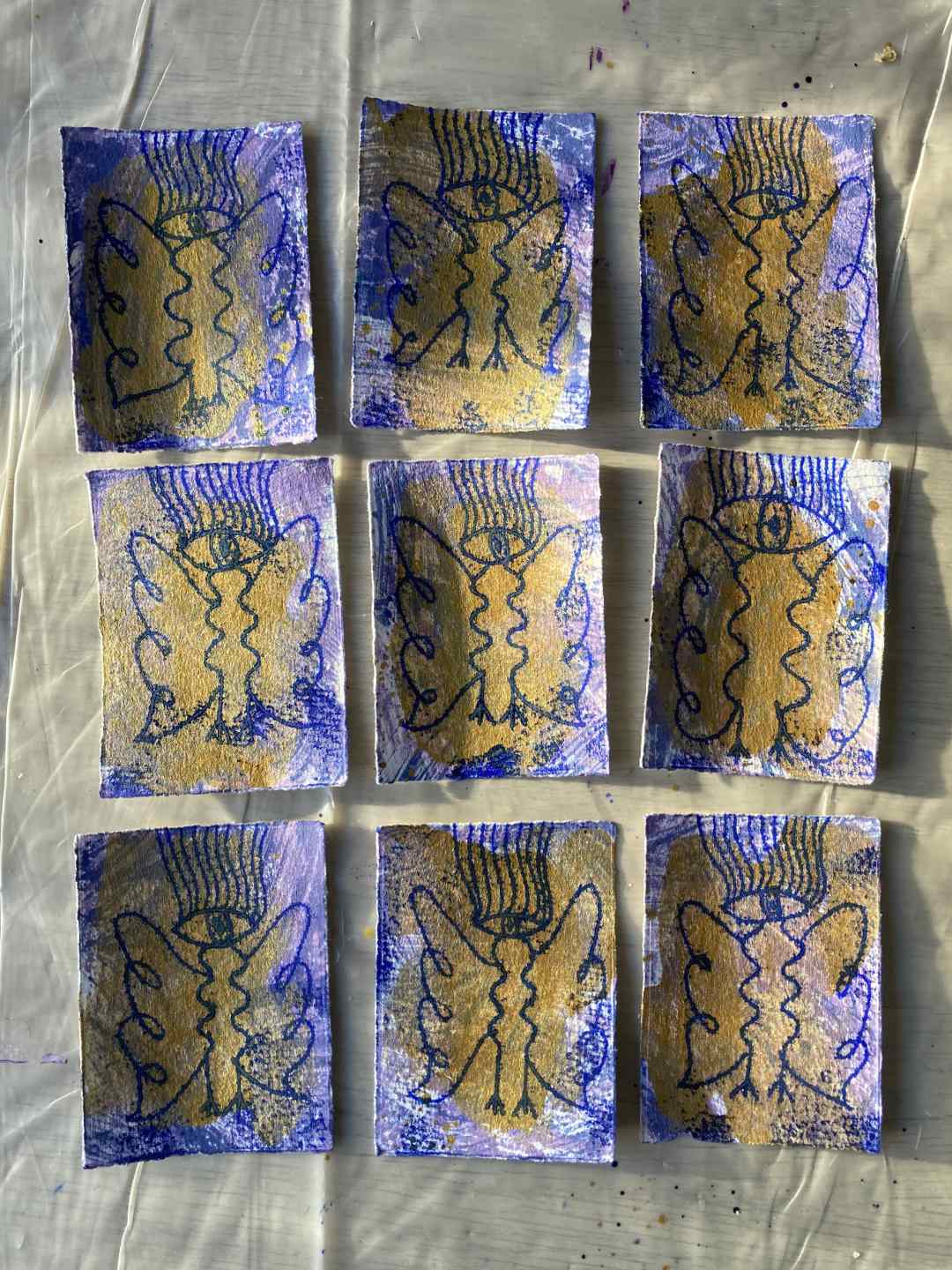 Großes Bild mit neun Drucken aus der zweiten Serie. 3x3 gelegt. Die Sonne spielt auf dem Tisch mit Licht, das Gold der Engel leuchtet.